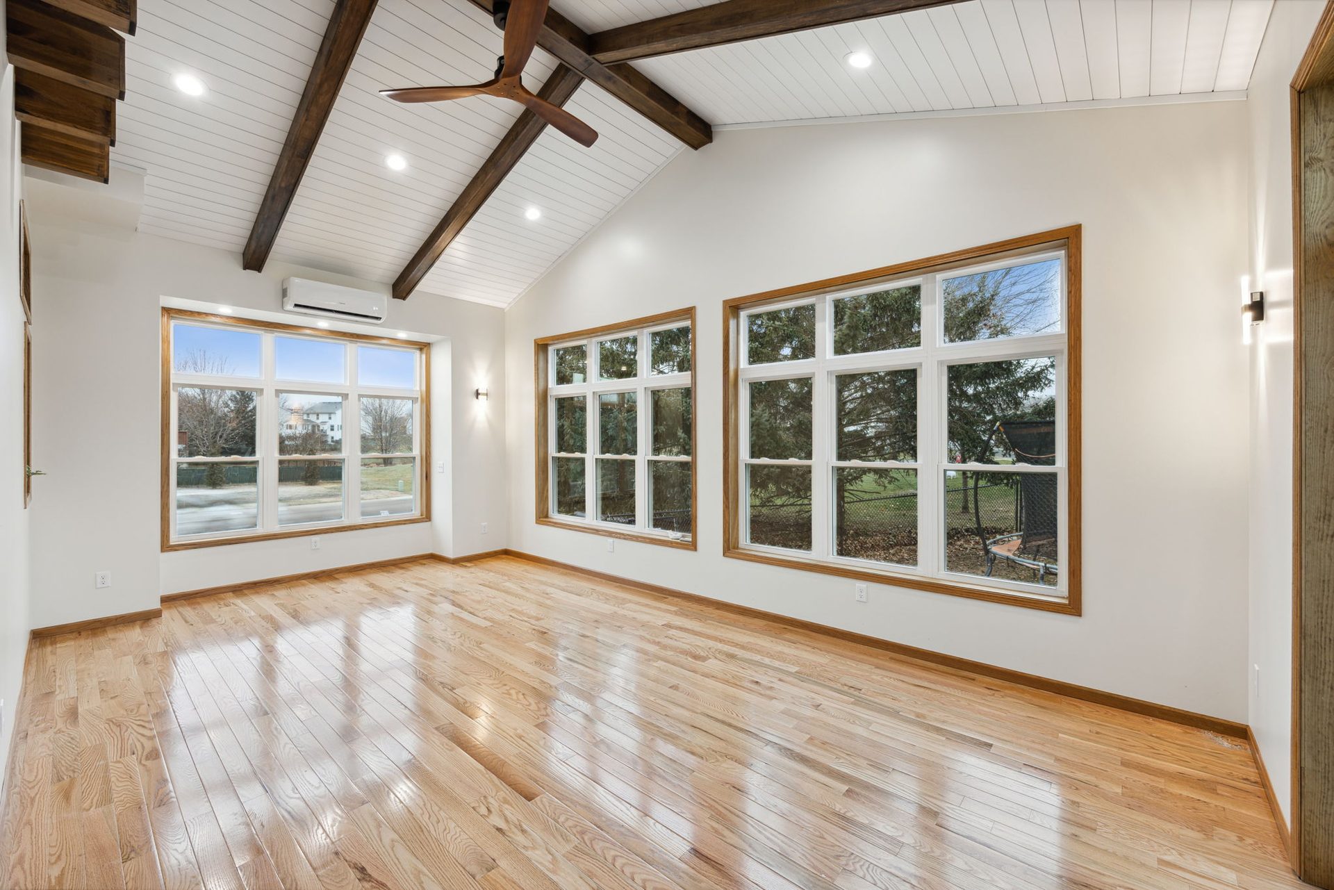 Vaulted addition with oak-trimmed windows on two walls, a ductless mini-split head and oak flooring