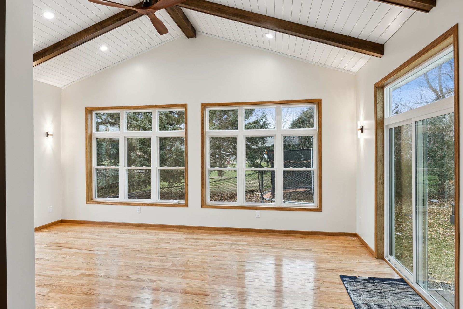 Four-season addition with oak-trimmed double windows, a sliding door to the deck and light oak flooring