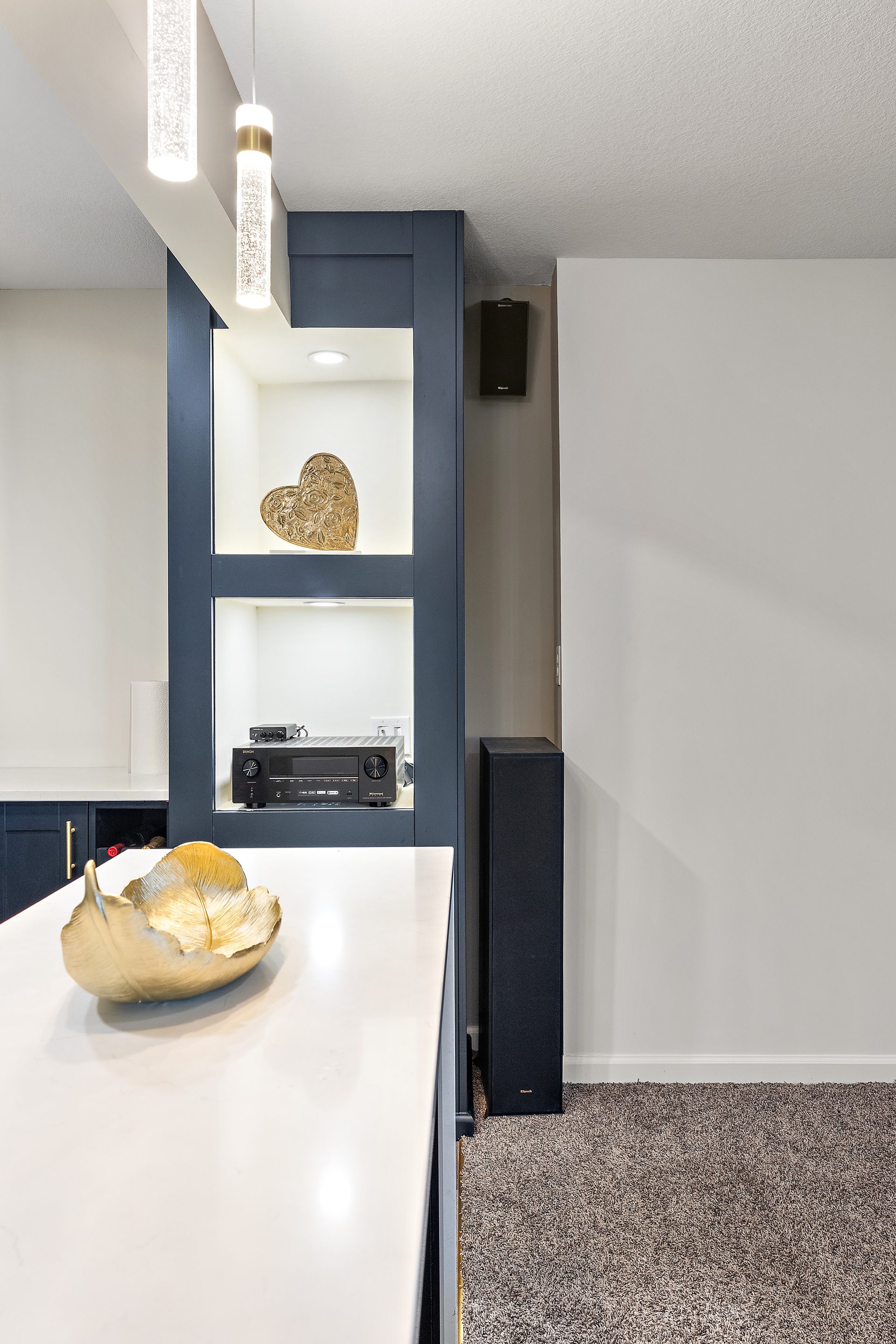Navy open shelving and a quartz counter in a finished basement wet bar