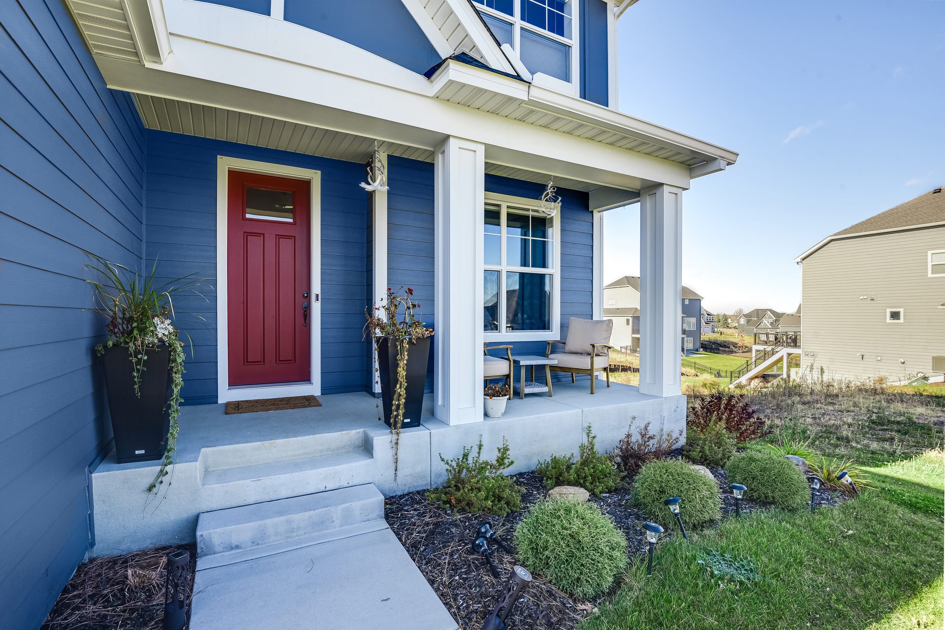 Front elevation with a covered porch, painted columns and a planted bed at the step
