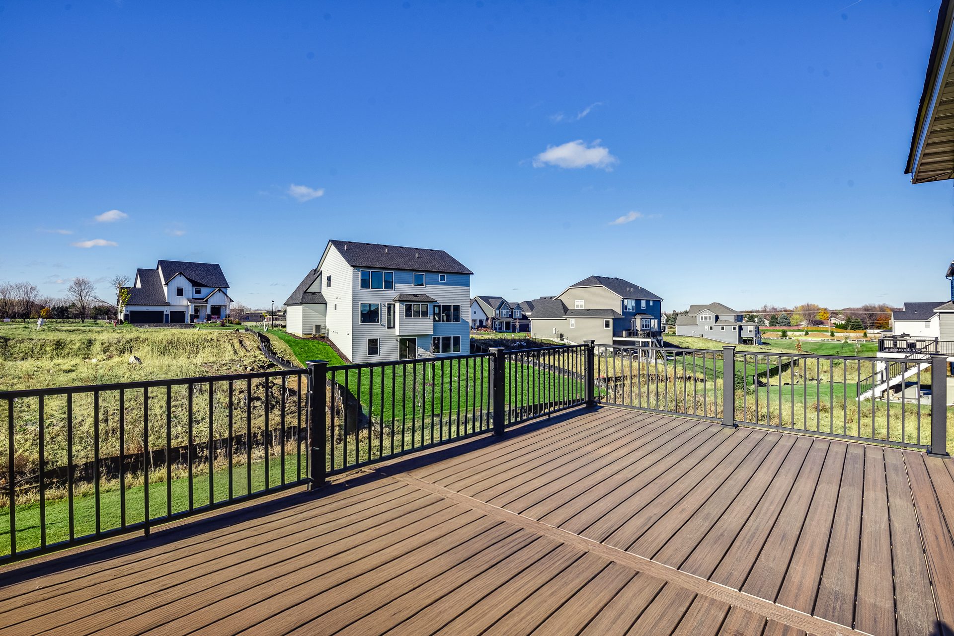 Composite deck with a black metal guard, looking across a lawn toward open ground