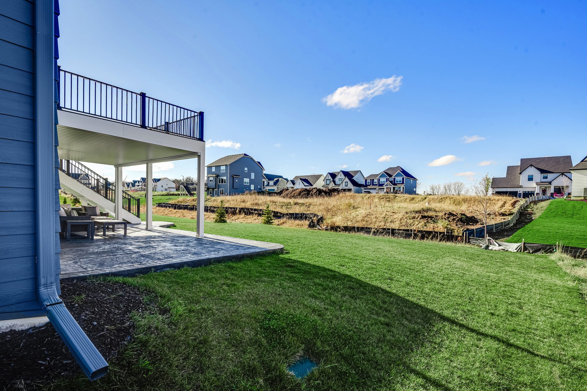 Rear elevation with an elevated deck above a covered patio, beside a sloping lawn