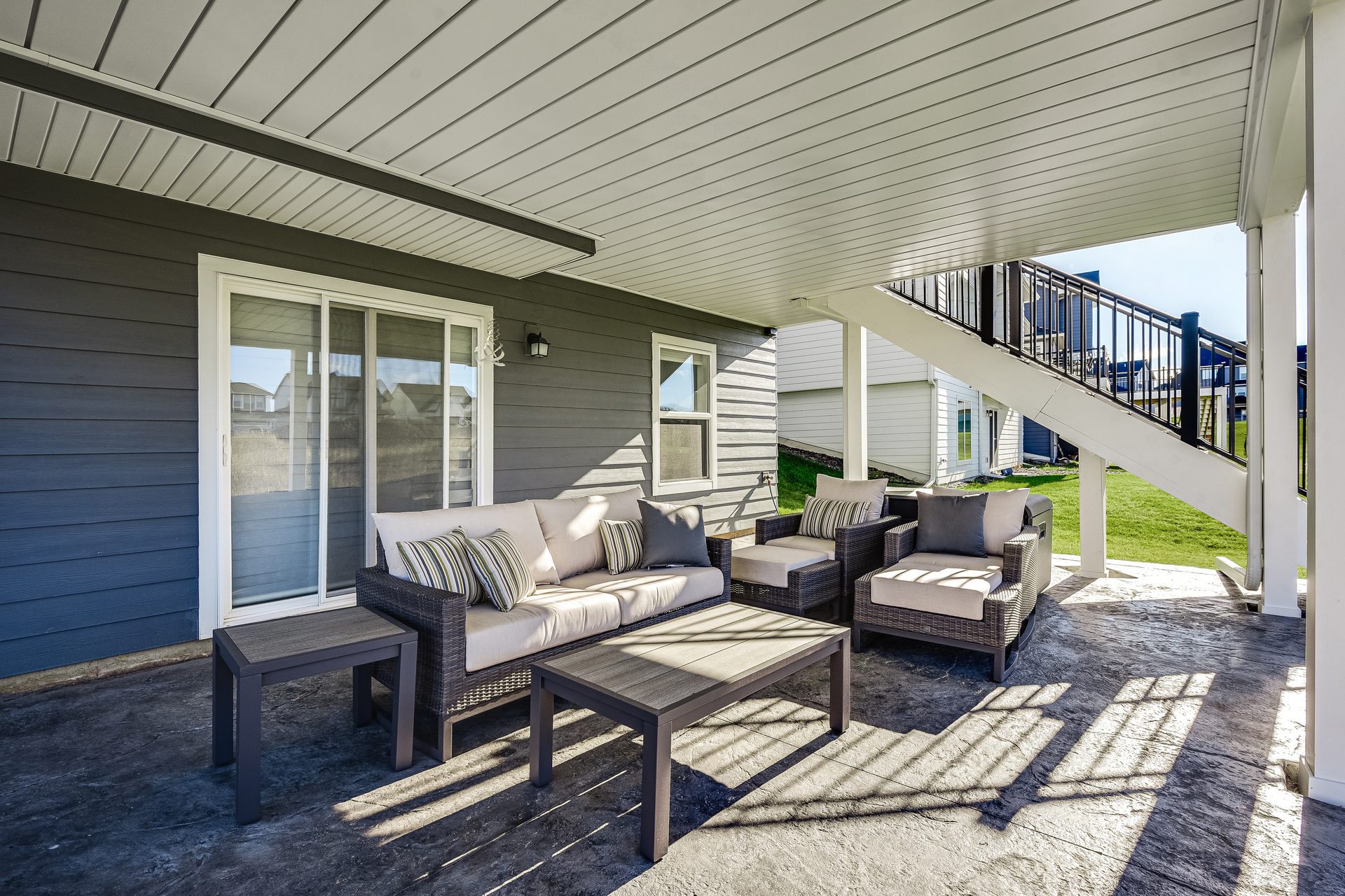 Covered patio beneath a deck, with a shiplap ceiling and the stair run beyond