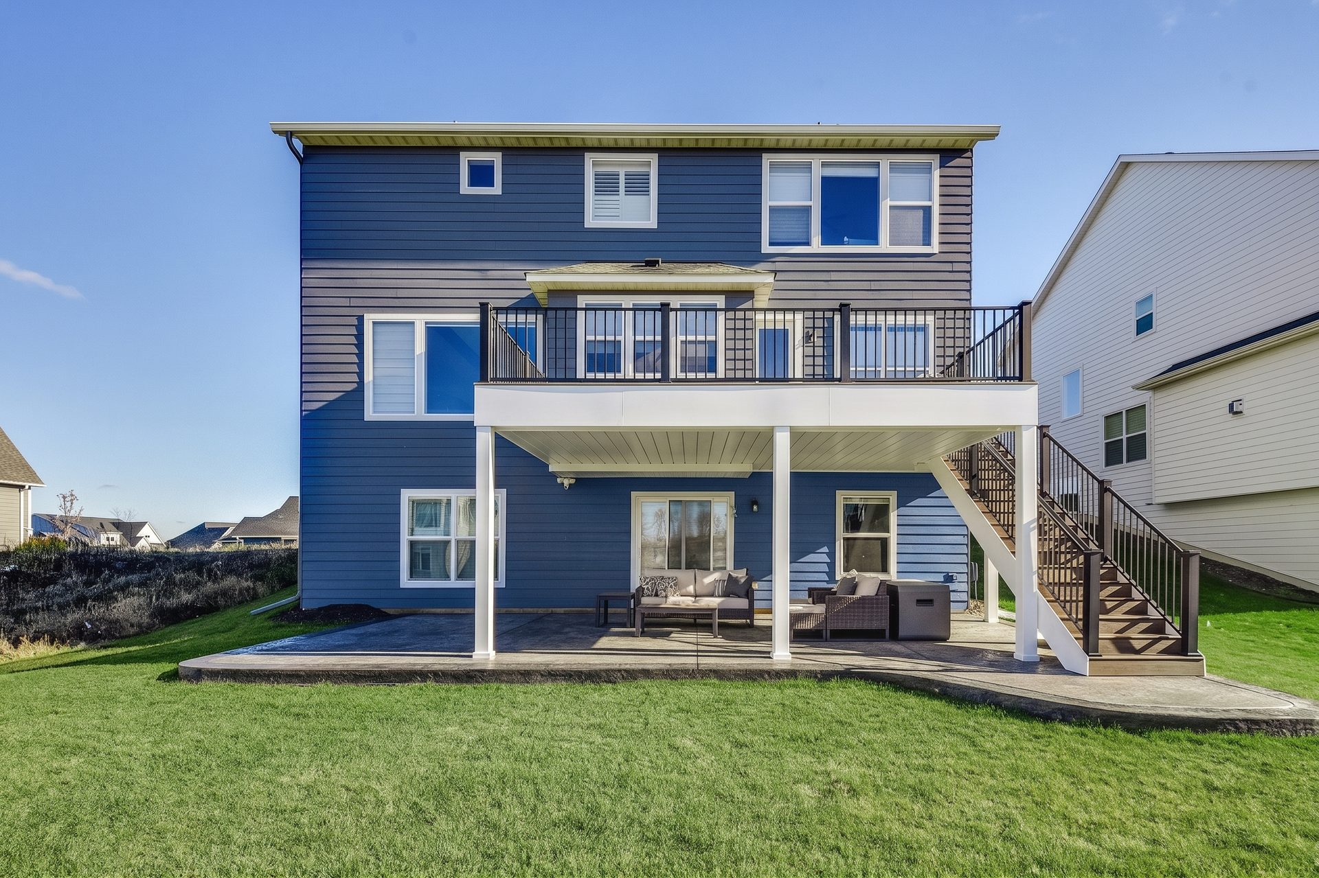 Rear elevation of a two-story house with an elevated deck over a covered lower patio