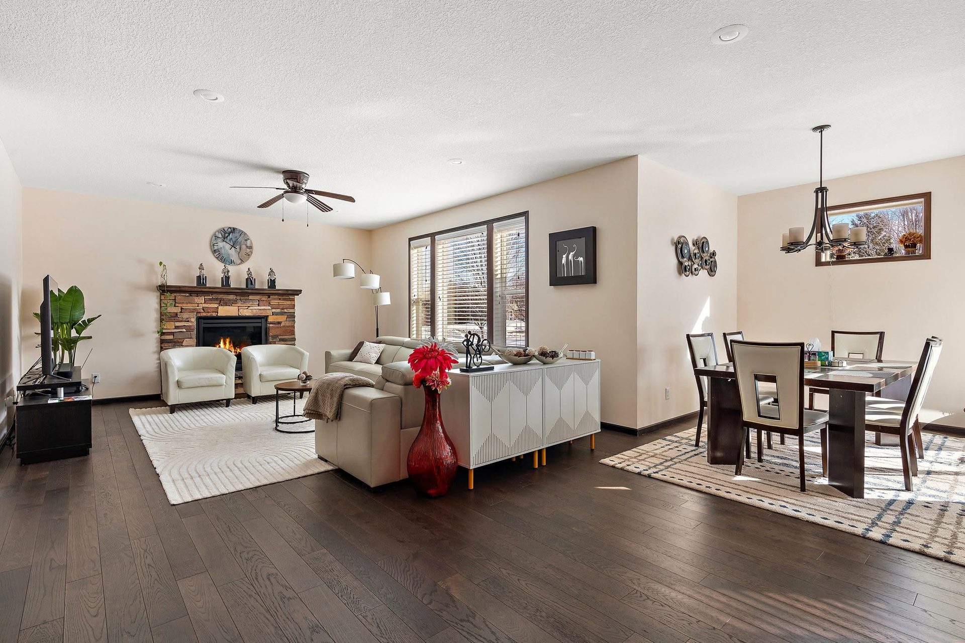 Open living and dining space with a stone fireplace and dark hardwood flooring