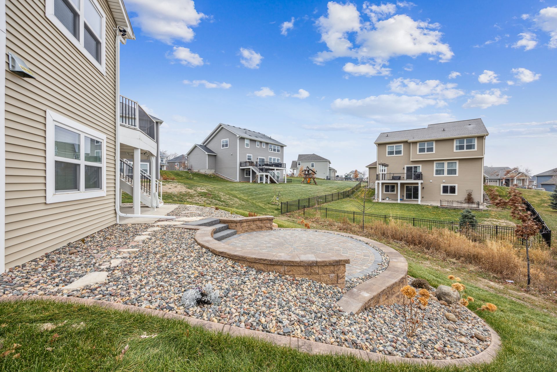 Raised paver patio with a seat wall and a fire pit set into a stone bed