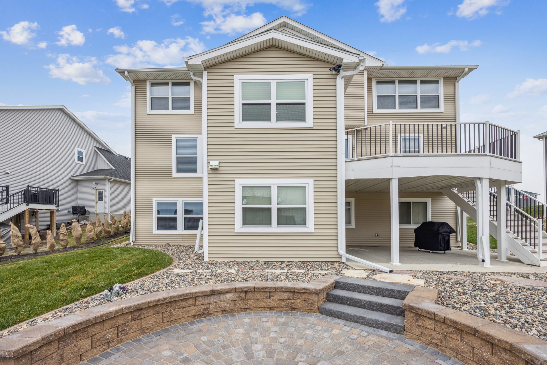 Rear elevation with a paver patio, seat wall and steps up to a covered area
