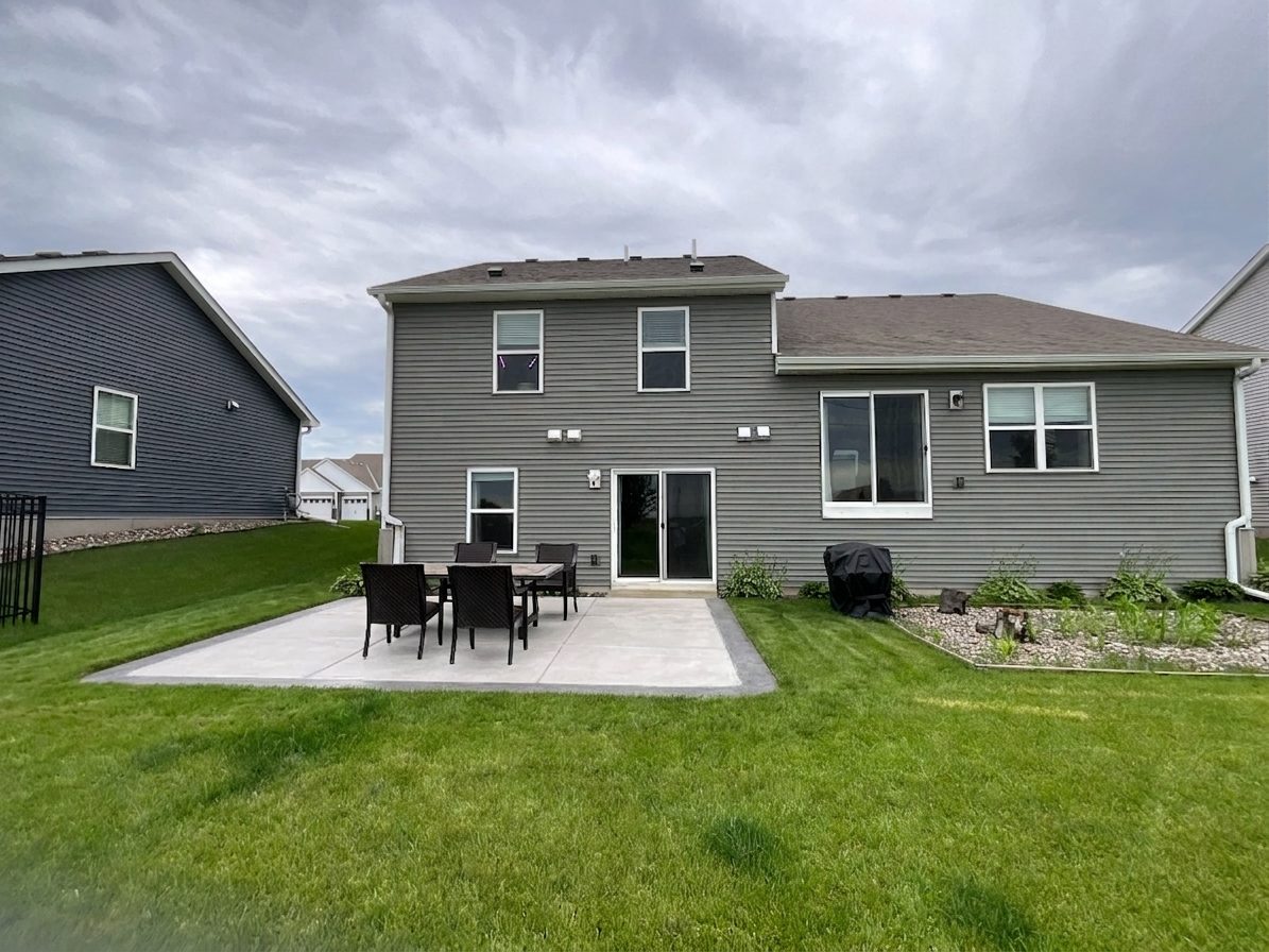Concrete patio with outdoor seating against a rear elevation