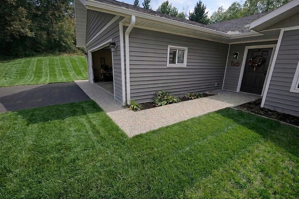 A resin-bound apron laid joint-free between the drive and a front entry, finished flush to the lawn edge