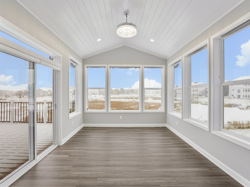 A four-season sunroom with a vaulted ceiling and a wall of windows.