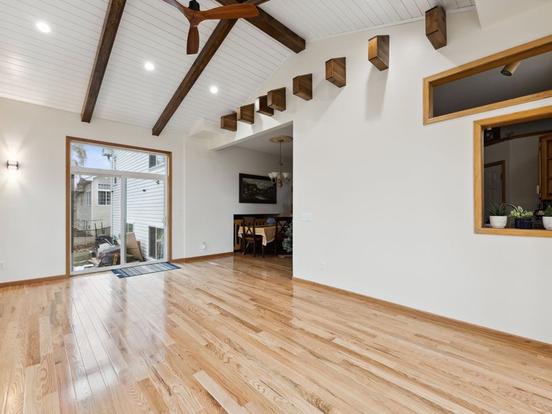 An addition interior with exposed beams and wide-plank flooring.