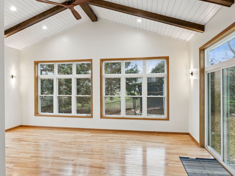 A sunroom addition opening onto a deck through sliding doors.
