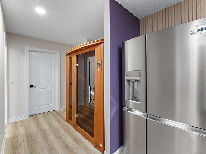 A cedar and glass sauna cabin built into a finished basement.