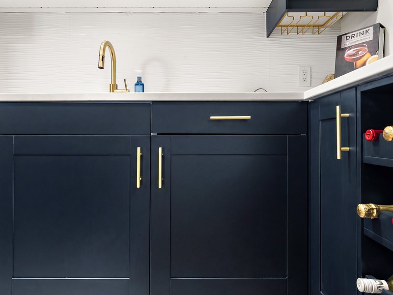 A basement wet bar with navy cabinetry and a quartz counter.