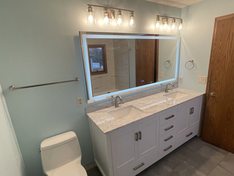 A bathroom vanity with a backlit mirror and quartz top.