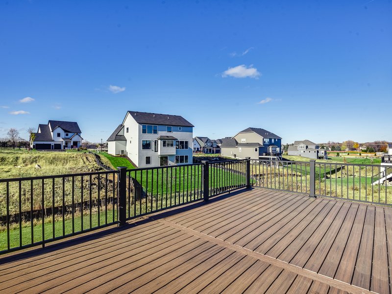 A composite deck surface with aluminum guard and downspout beyond.