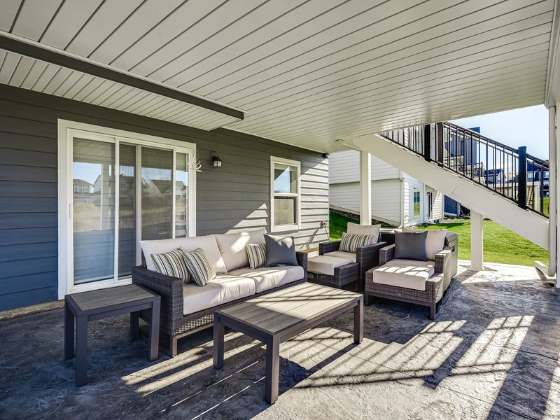 A covered lower patio beneath a deck, with the drainage ceiling above.