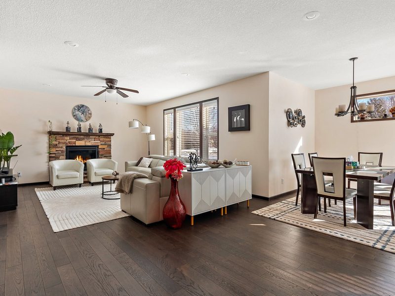 An open living and dining space with a stone fireplace and dark hardwood flooring.