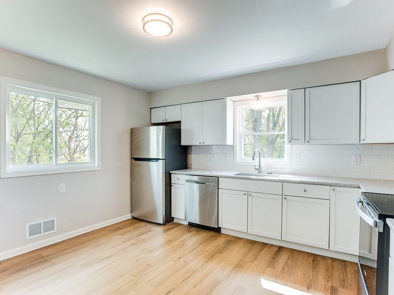 A kitchen with white shaker cabinetry, a subway tile backsplash and stainless appliances.